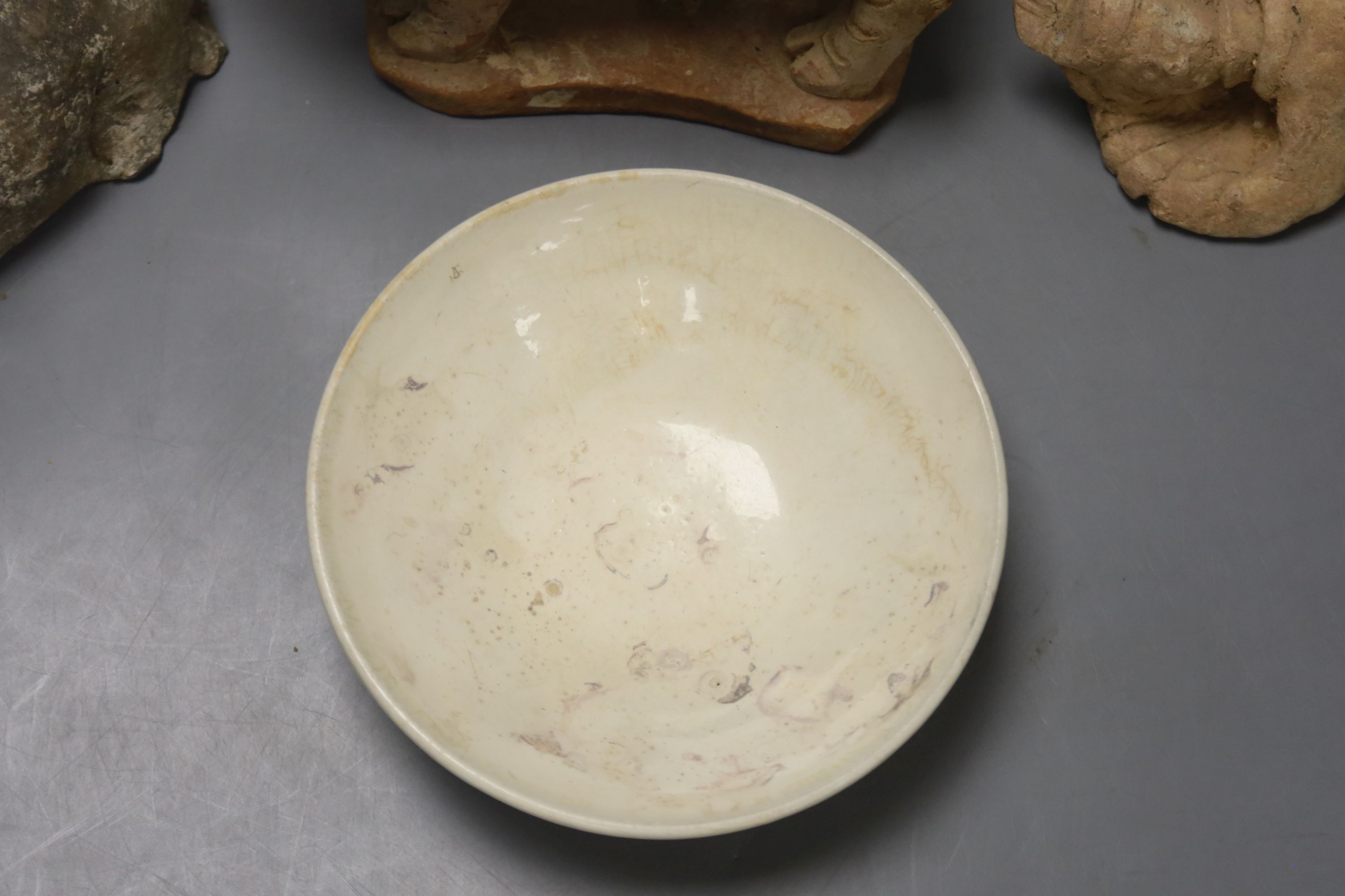 A Chinese Han terracotta model of a standing pig, 17cm long 12cm high, together with two further modelled terracotta figures and a small white glazed Chinese porcelain footed dish, diameter 14cm 4cm high